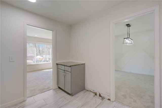 corridor with baseboards and light colored carpet