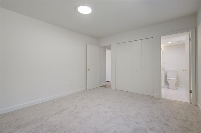 unfurnished bedroom featuring ensuite bathroom, baseboards, carpet flooring, and a closet