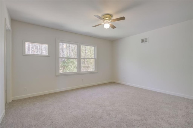 unfurnished room with light colored carpet, visible vents, a ceiling fan, and baseboards
