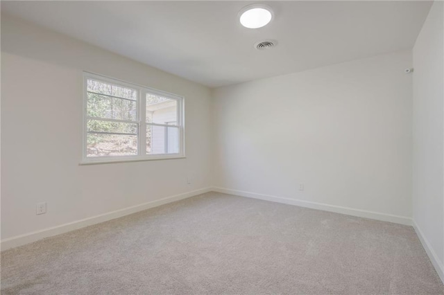 spare room featuring baseboards, visible vents, and light colored carpet