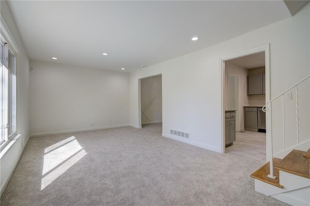 unfurnished room featuring light colored carpet, visible vents, recessed lighting, and baseboards