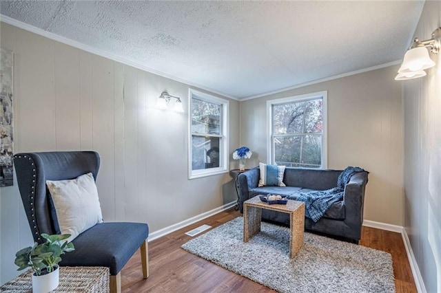 living area with crown molding, hardwood / wood-style flooring, and a textured ceiling