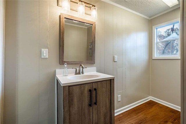 bathroom with vanity, wood-type flooring, ornamental molding, and a textured ceiling