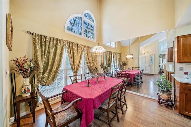 dining area with a chandelier, a high ceiling, a wealth of natural light, and light wood-style floors