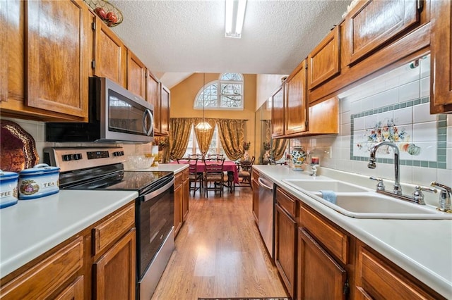 kitchen featuring stainless steel appliances, a sink, light countertops, and brown cabinets