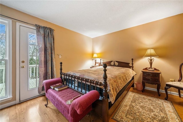 bedroom with baseboards, access to outside, and light wood-style floors