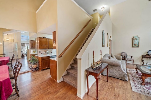 stairs featuring baseboards, visible vents, a high ceiling, and wood finished floors