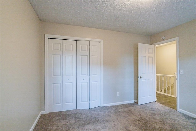 unfurnished bedroom with a textured ceiling, a closet, and carpet flooring