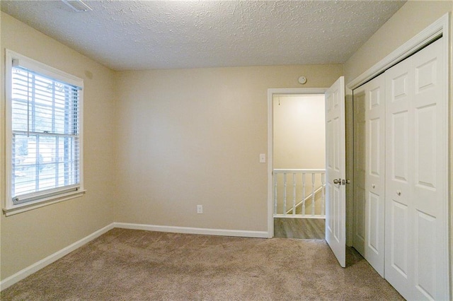 unfurnished bedroom with a closet, a textured ceiling, and light colored carpet