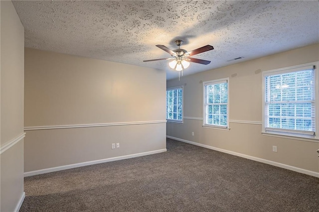 empty room with dark carpet, a textured ceiling, and ceiling fan