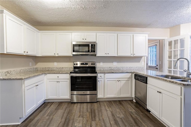 kitchen featuring sink, white cabinets, stainless steel appliances, dark hardwood / wood-style flooring, and light stone countertops