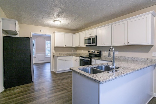 kitchen with a textured ceiling, white cabinets, kitchen peninsula, stainless steel appliances, and dark hardwood / wood-style flooring