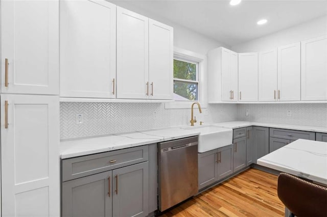 kitchen featuring light stone counters, gray cabinetry, stainless steel dishwasher, and tasteful backsplash