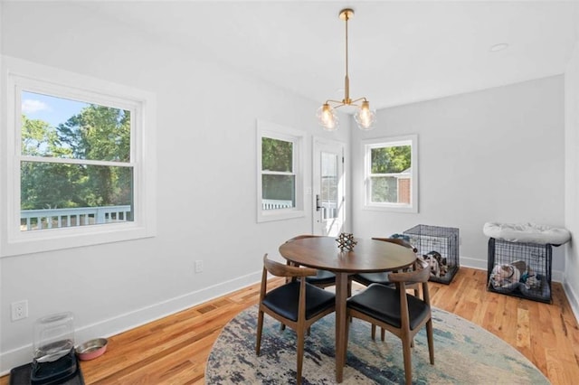 dining room featuring light wood-type flooring, baseboards, and a notable chandelier