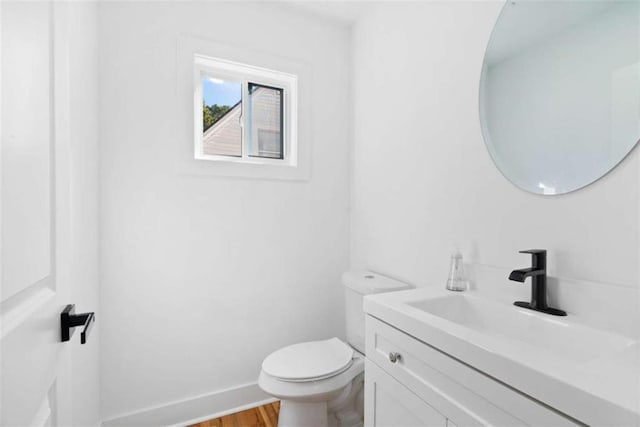 bathroom with toilet, baseboards, wood finished floors, and vanity