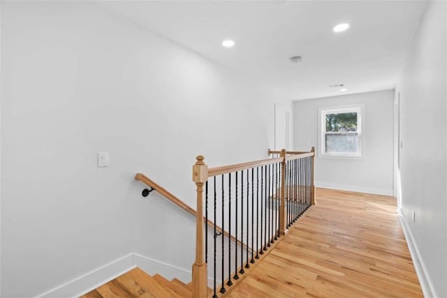 hallway with light wood-style floors, recessed lighting, baseboards, and an upstairs landing