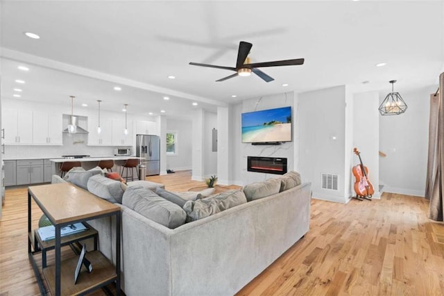 living area with light wood-type flooring, a fireplace, visible vents, and recessed lighting