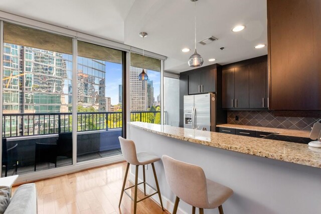 1080 Peachtree St NE Unit 608, Atlanta, GA 30309 - kitchen featuring stainless steel refrigerator with ice dispenser, a city view, tasteful backsplash, dark brown cabinets, and a breakfast bar