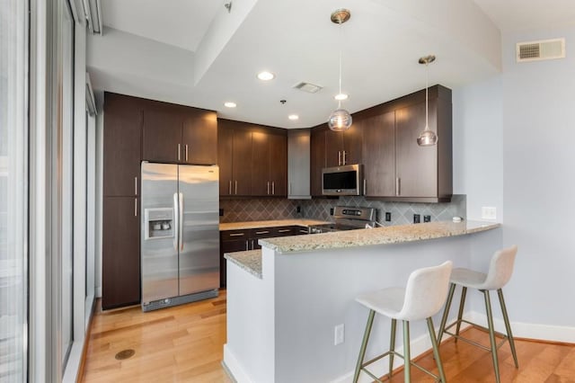1080 Peachtree St NE Unit 608, Atlanta, GA 30309 - kitchen featuring appliances with stainless steel finishes, a peninsula, tasteful backsplash, light wood-style floors, and dark brown cabinetry