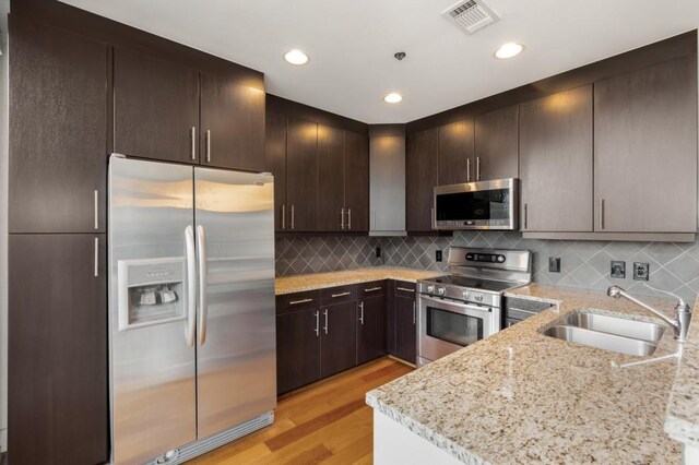1080 Peachtree St NE Unit 608, Atlanta, GA 30309 - kitchen featuring appliances with stainless steel finishes, a sink, light wood-style floors, light stone countertops, and tasteful backsplash