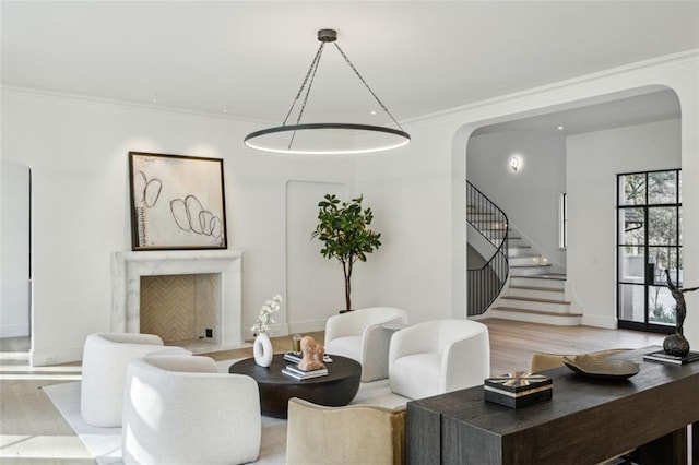 living room featuring light wood-type flooring, ornamental molding, and a premium fireplace