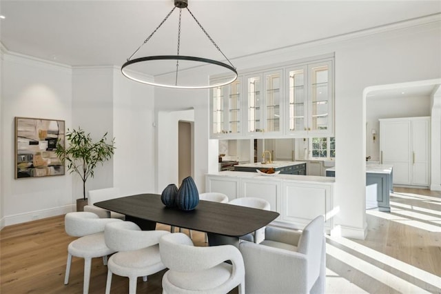 dining space featuring ornamental molding and light hardwood / wood-style flooring