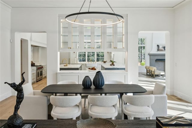 dining area with light hardwood / wood-style floors, an inviting chandelier, a wealth of natural light, and crown molding