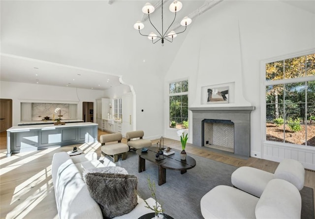 living room featuring an inviting chandelier, light hardwood / wood-style flooring, and high vaulted ceiling