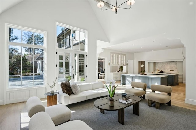 living room with a healthy amount of sunlight, high vaulted ceiling, and light hardwood / wood-style flooring