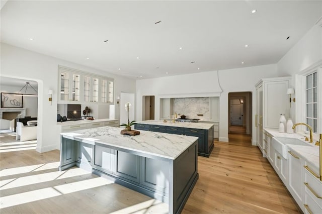 kitchen with white cabinets, light hardwood / wood-style floors, sink, and an island with sink