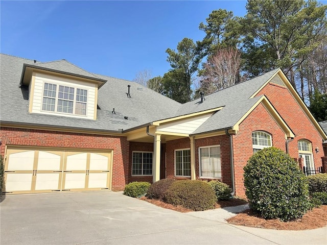 view of front of property with driveway, brick siding, and a shingled roof