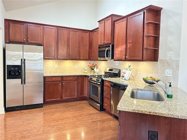 kitchen with open shelves, stainless steel appliances, light wood-style floors, vaulted ceiling, and a sink