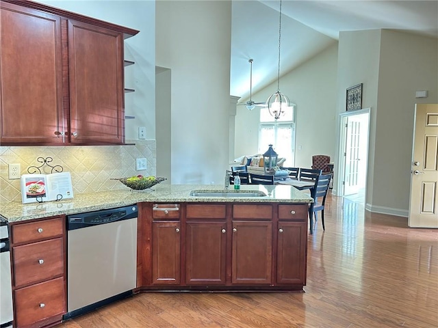 kitchen featuring dishwasher, light wood-style flooring, a peninsula, light stone countertops, and a sink