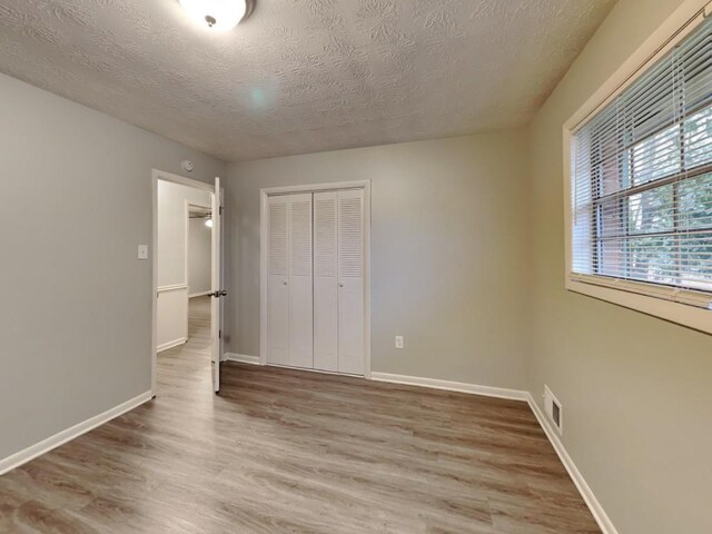 unfurnished bedroom with dark wood-type flooring and a closet