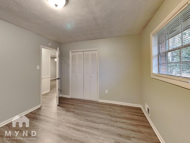 unfurnished bedroom featuring hardwood / wood-style flooring, a textured ceiling, and a closet