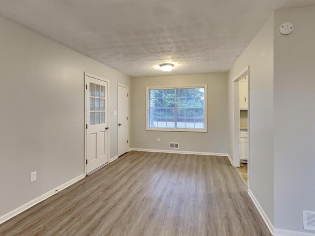 unfurnished room featuring ceiling fan, light hardwood / wood-style floors, and a textured ceiling