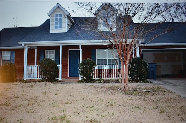 cape cod home featuring covered porch and a garage