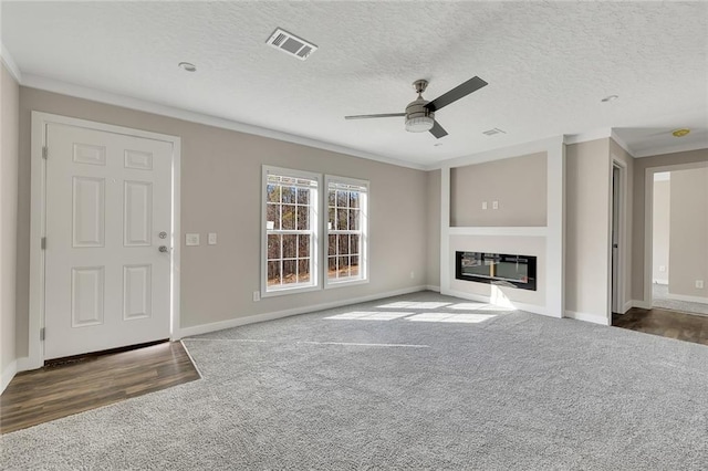 unfurnished living room with dark wood-type flooring, a textured ceiling, and ornamental molding