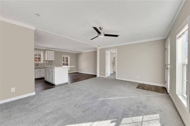 unfurnished living room with ceiling fan, sink, dark wood-type flooring, and ornamental molding