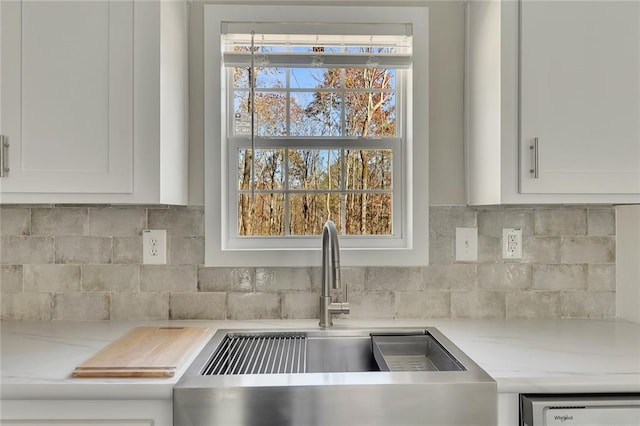 kitchen with decorative backsplash, light stone countertops, white cabinetry, and sink