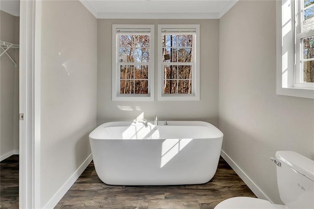 bathroom featuring toilet, a washtub, ornamental molding, and hardwood / wood-style flooring