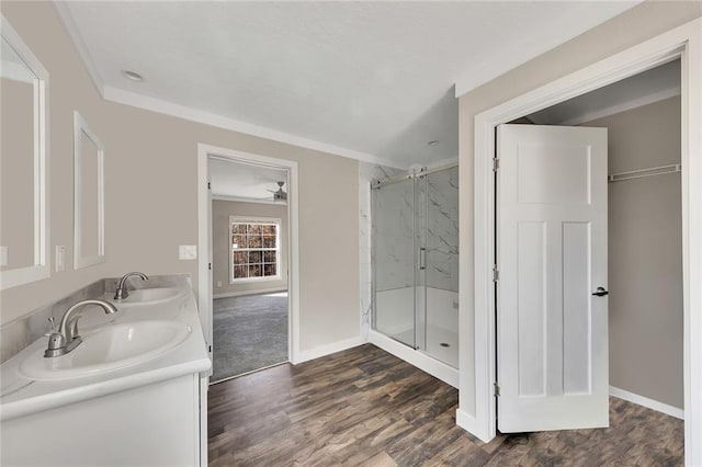 bathroom featuring a shower with shower door, ceiling fan, wood-type flooring, and vanity