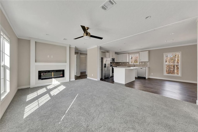 unfurnished living room with built in shelves, ceiling fan, sink, dark hardwood / wood-style flooring, and crown molding