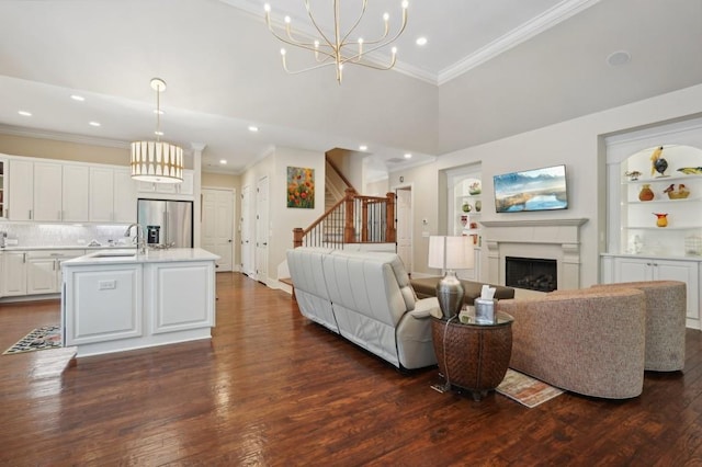 living room featuring sink, a high ceiling, a notable chandelier, dark hardwood / wood-style floors, and built in shelves