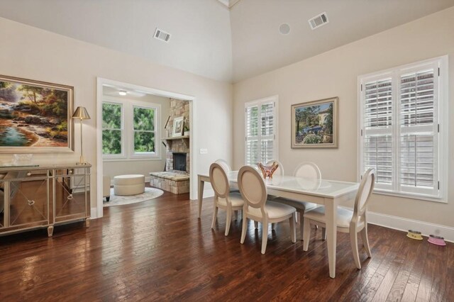 dining space featuring high vaulted ceiling, a healthy amount of sunlight, dark hardwood / wood-style flooring, and a fireplace