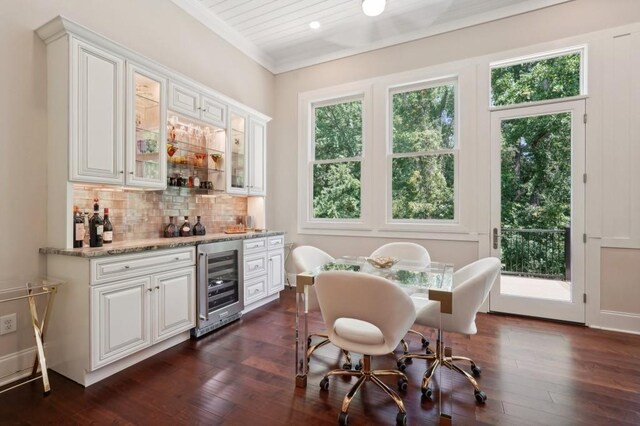 interior space featuring white cabinets, light stone counters, dark hardwood / wood-style floors, and beverage cooler