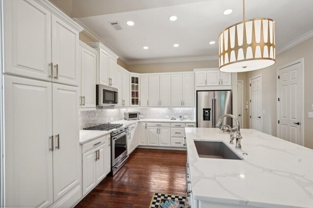 kitchen with dark wood-type flooring, hanging light fixtures, stainless steel appliances, sink, and white cabinetry