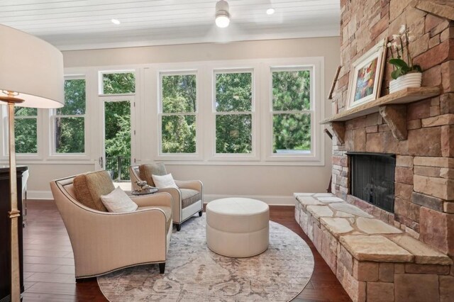 living room featuring a stone fireplace, wood-type flooring, and a healthy amount of sunlight