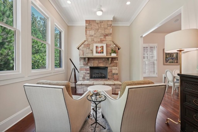 living room with dark wood-type flooring, ornamental molding, and a fireplace