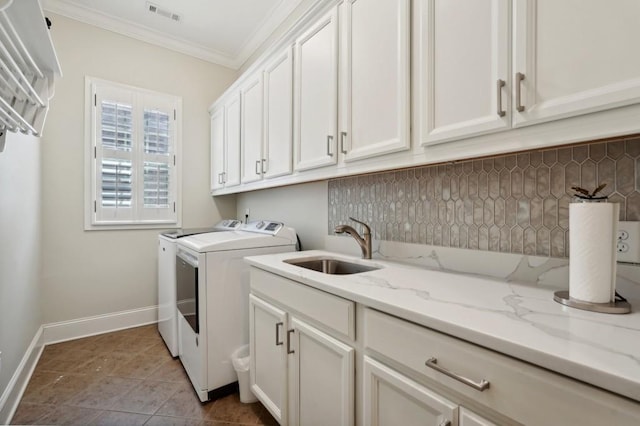 clothes washing area featuring cabinets, light tile patterned floors, ornamental molding, sink, and washer and clothes dryer